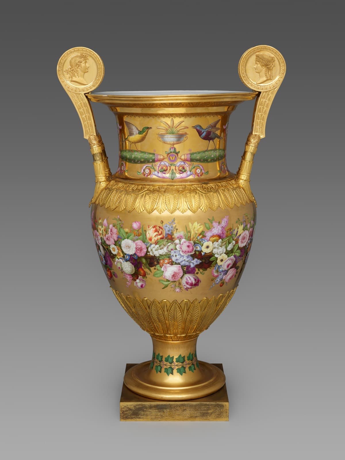 A Sèvres porcelain vase covered in burnished gold with a painted garland of flowers and medallion handles.