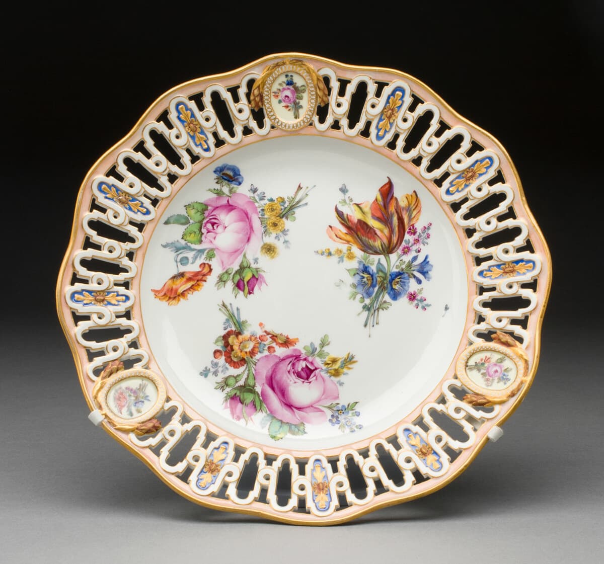 A Meissen porcelain plate with a pierced rim, pink and gilt border and hand-painted floral sprays.