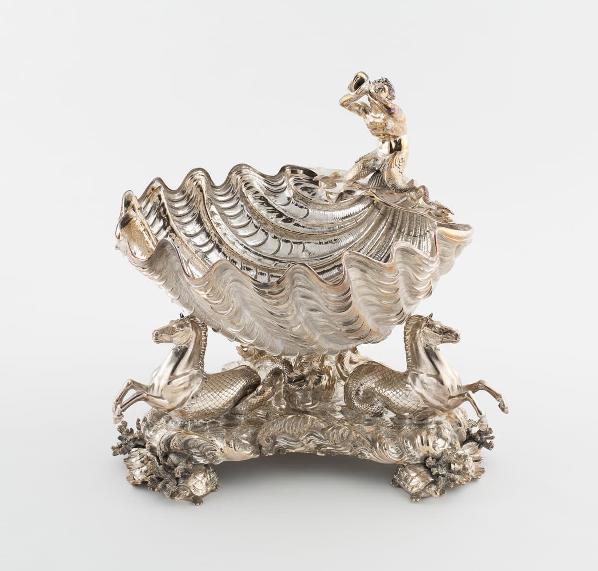 A chased silver centerpiece formed as a scallop shell raised on sea-horses and coral.